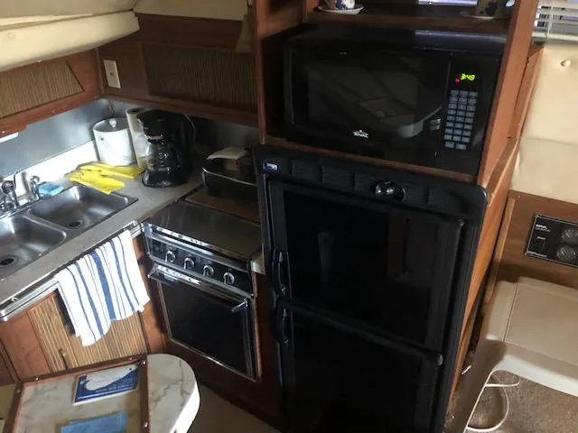 Slide: The Image of 1983 Sea Ray 390 Sport Fisherman kitchen with microwave, stove, fridge, and sink. - 24