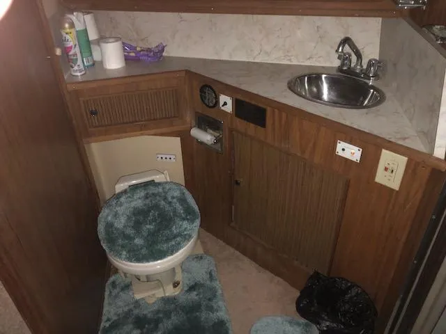 Slide: The Image of 1983 Sea Ray 390 Sport Fisherman bathroom with sink, toilet, and storage cabinets. - 28
