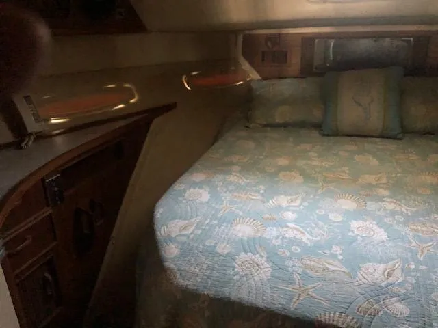 Slide: The Image of 1983 Sea Ray 390 Sport Fisherman cabin with a cozy bed and nautical-themed bedding. - 30