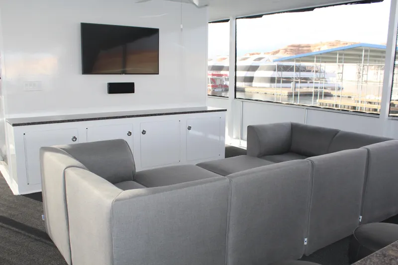 Slide: The Image of Modern houseboat interior with gray sofas, wall-mounted TV, and large windows. Adonia Rhapsody Share #11, 2019. - 12