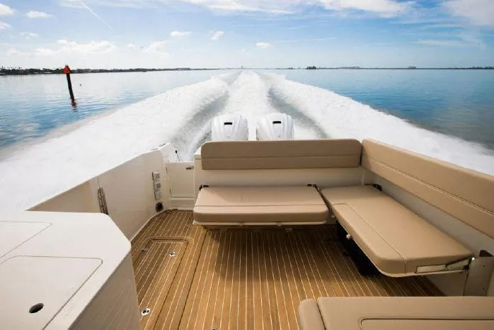 Slide: The Image of 2024 Southport 33 DC boat interior with cushioned seating and twin engines on calm water. - 3