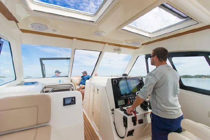 Slide: The Image of 2024 Southport 33 DC interior with captain at helm, passengers enjoying view. - 5