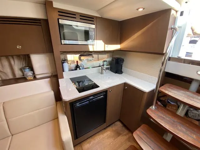 Slide: The Image of 2015 Sea Ray 350 Sundancer yacht kitchen with modern appliances and wooden cabinetry. - 11