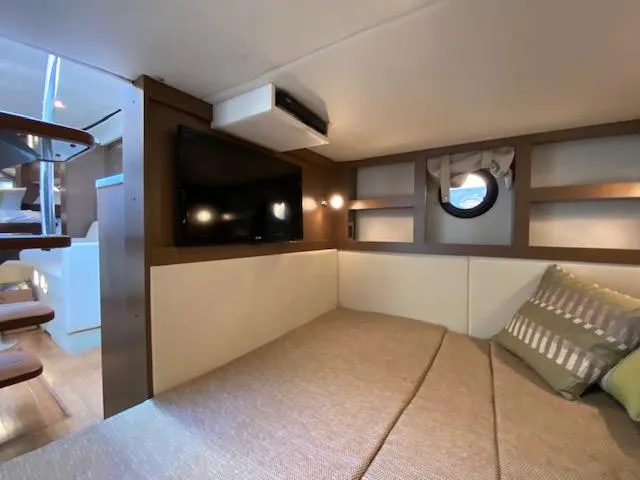 Slide: The Image of Interior cabin of 2015 Sea Ray 350 Sundancer with bed, TV, and porthole window. - 14