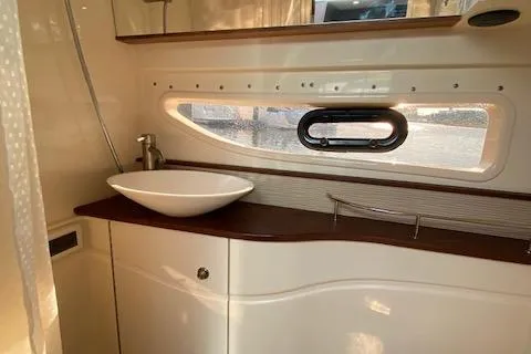 Slide: The Image of 2015 Sea Ray 350 Sundancer bathroom with modern sink and porthole window. - 15