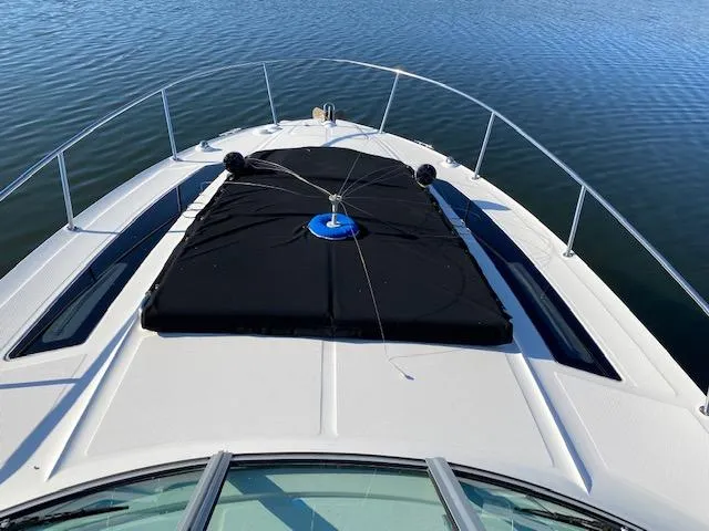Slide: The Image of 2015 Sea Ray 350 Sundancer boat deck with black cover on calm water. - 2