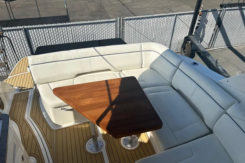 Slide: The Image of 2015 Sea Ray 350 Sundancer boat with white seating and wooden table on deck. - 7