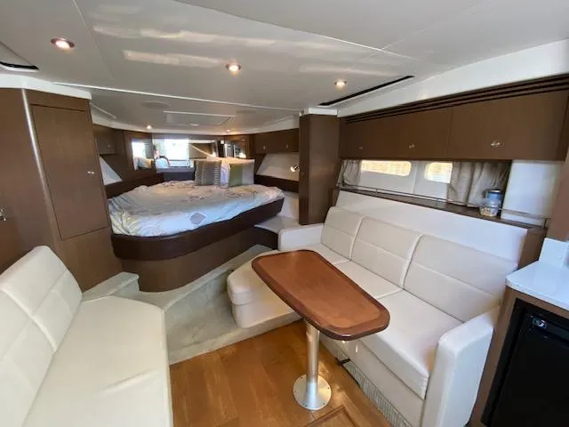 Slide: The Image of 2015 Sea Ray 350 Sundancer interior with cozy seating, dining table, and bed. - 9