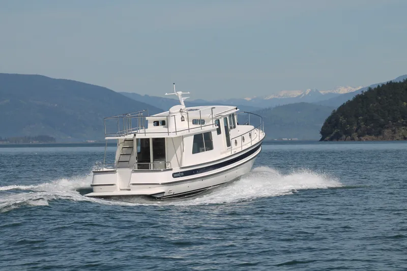 Slide: The Image of Nordic Tug 40 (2025) cruising on a scenic lake with mountainous backdrop. - 4