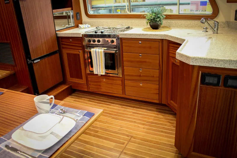 Slide: The Image of Modern kitchen in 2025 Nordic Tug 40 yacht with wooden cabinetry and dining setup. - 5
