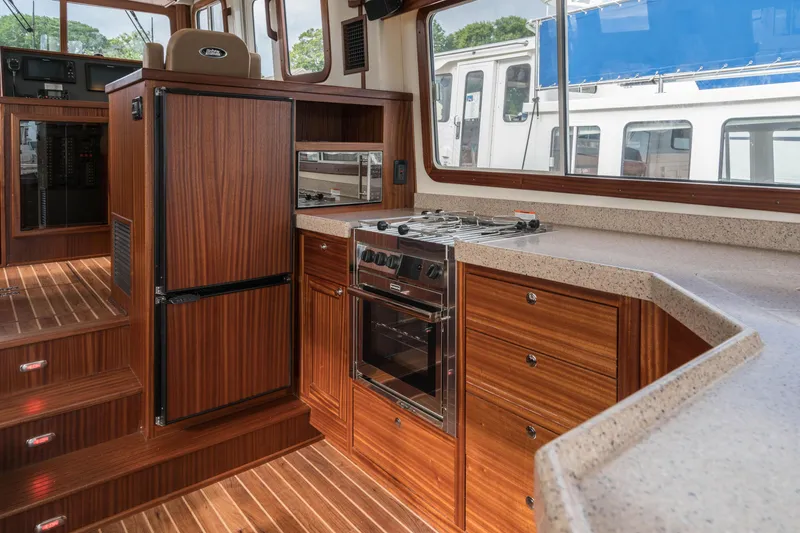 Slide: The Image of 2025 Nordic Tug 40 yacht kitchen with wood cabinetry, stove, and refrigerator. - 7