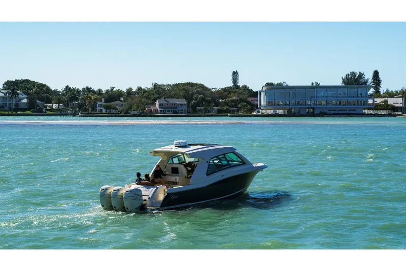 Slide: The Image of 2023 Scout 350 LXZ boat cruising on a sunny day near the shore. - 21