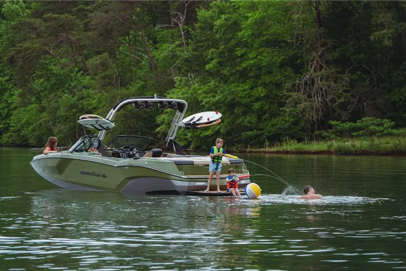 Slide: The Image of 2023 MasterCraft NXT24 boat on a lake with people swimming and playing. - 1
