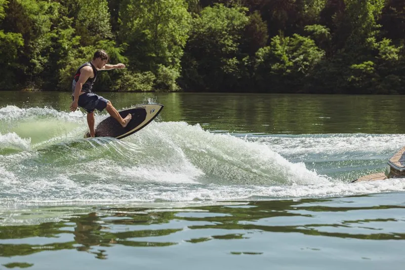 Slide: The Image of Man wakesurfing behind a 2023 MasterCraft NXT24 boat on a lake. - 7