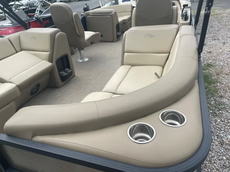 Slide: The Image of 2021 Manitou 230 Aurora LE pontoon boat interior with beige seating and cup holders. - 14