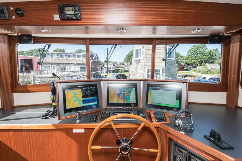 Slide: The Image of Nordic Tug 44 2025 helm station with navigation screens and wooden steering wheel. - 6
