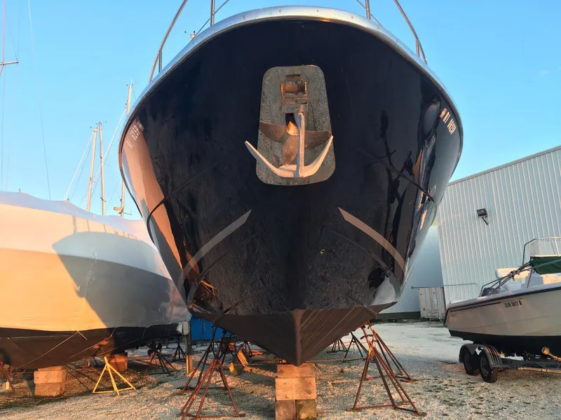 Slide: The Image of 2004 Baia 54 yacht on dry dock, front view, with anchor, in a boatyard setting. - 26