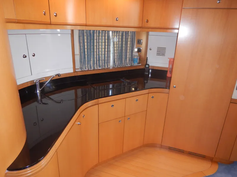 Slide: The Image of 2004 Baia 54 yacht kitchen with sleek wood cabinetry and black countertops. - 31