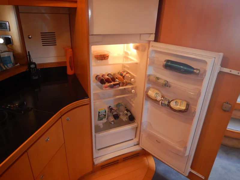 Slide: The Image of Open refrigerator in 2004 Baia 54 yacht kitchen, stocked with beverages and food items. - 32