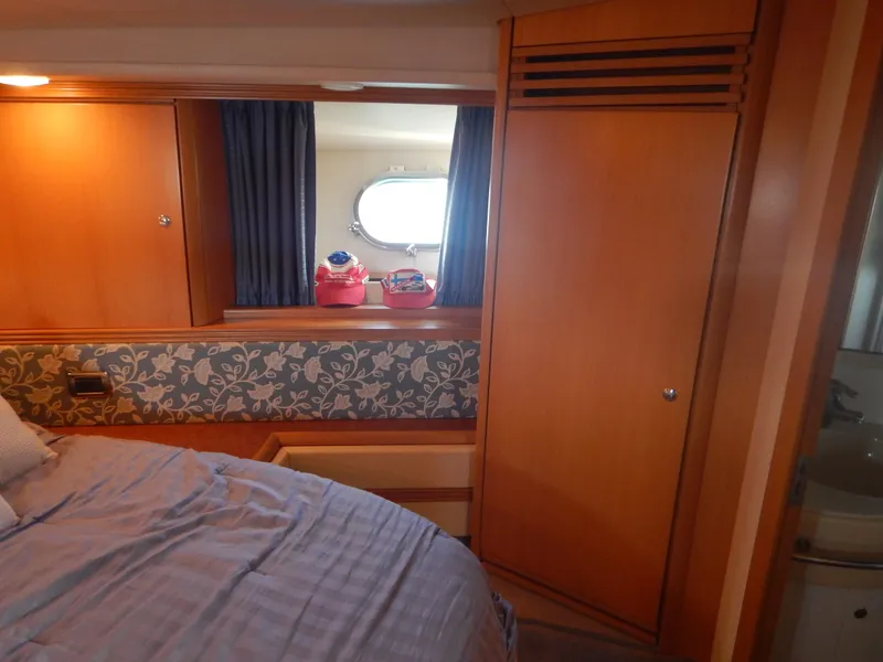 Slide: The Image of Cozy cabin interior of 2004 Baia 54 yacht with wooden furnishings and porthole. - 36