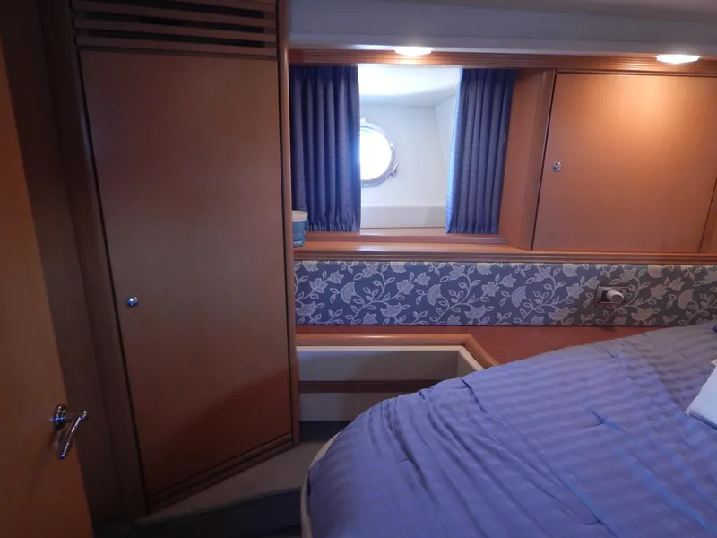 Slide: The Image of Cozy cabin interior of 2004 Baia 54 yacht with bed, window, and wooden cabinetry. - 37