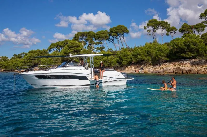 Slide: The Image of 2024 Jeanneau Leader 10.5 WA S2 boat anchored near a scenic coastline with people enjoying water activities. - 5