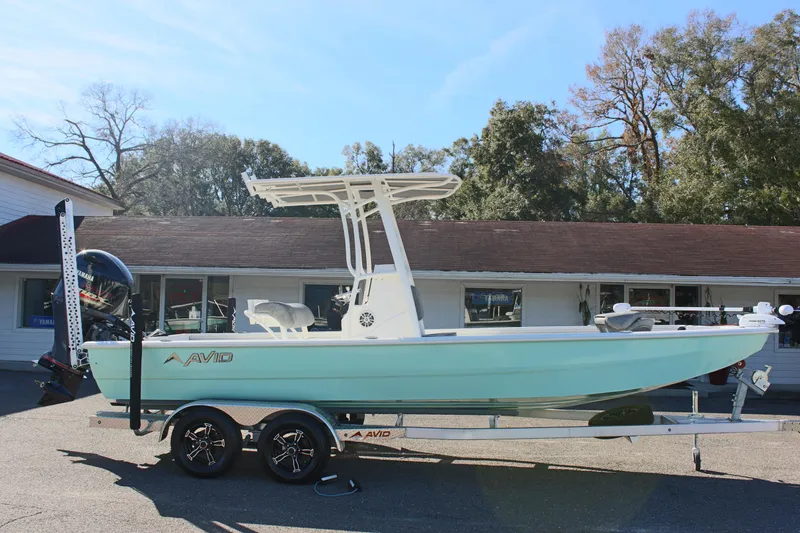 Slide: The Image of 2023 Avid AVID 23 MAG boat on trailer, light blue hull, parked outdoors. - 2