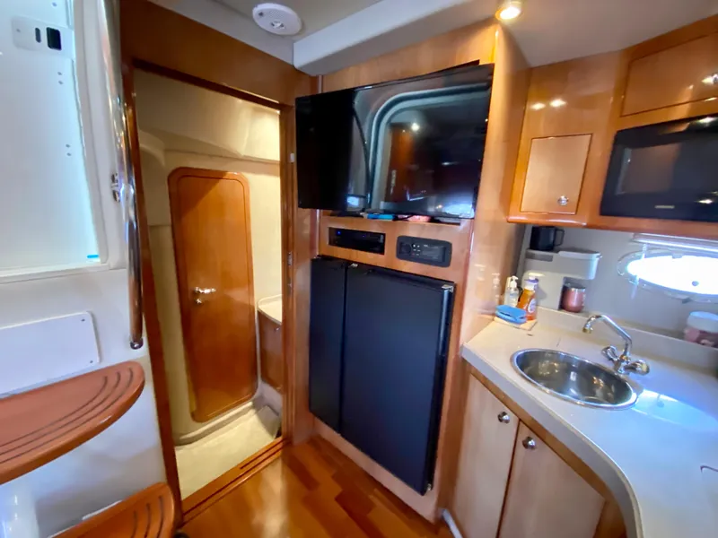 Slide: The Image of 2002 Regal 3860 Commodore yacht interior with kitchenette, TV, and wooden cabinetry. - 23
