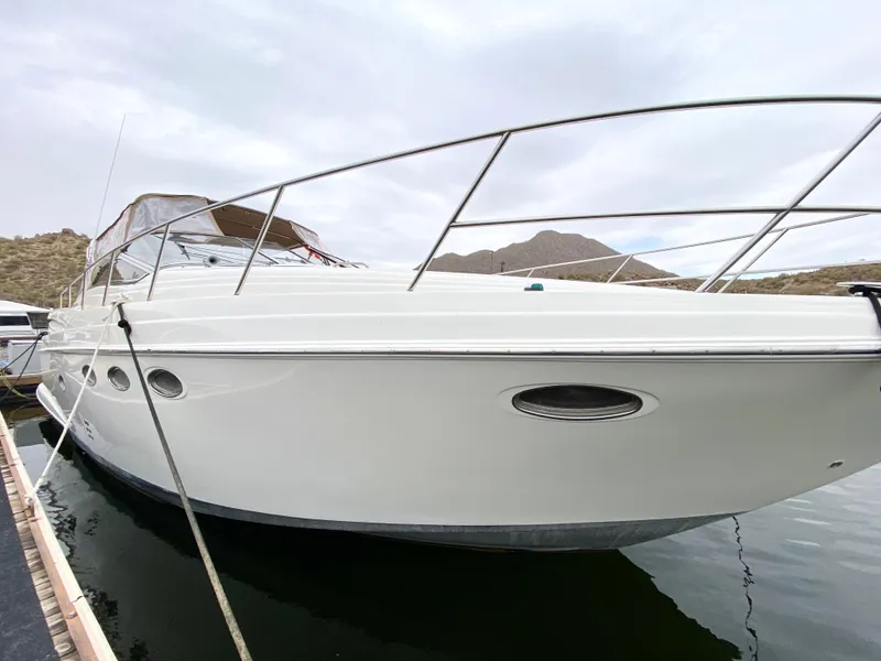 Slide: The Image of 2002 Regal 3860 Commodore yacht docked on calm water, mountainous background. - 3