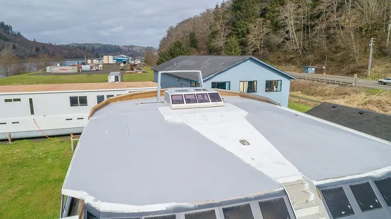 Slide: The Image of 2025 Catamaran Bloomfield 86 Motorsailor with solar panels, docked near buildings and trees. - 16