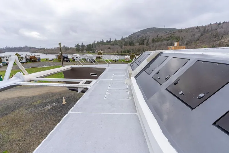 Slide: The Image of 2025 Catamaran Bloomfield 86 Motorsailor deck with sleek design and scenic background. - 34