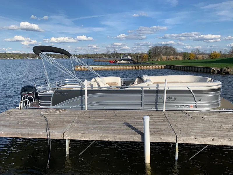 Slide: The Image of 2014 Harris Solstice 240 pontoon boat docked on a sunny lake. - 10