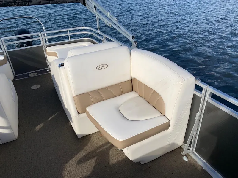Slide: The Image of 2014 Harris Solstice 240 pontoon boat with white and beige seating on a calm lake. - 6