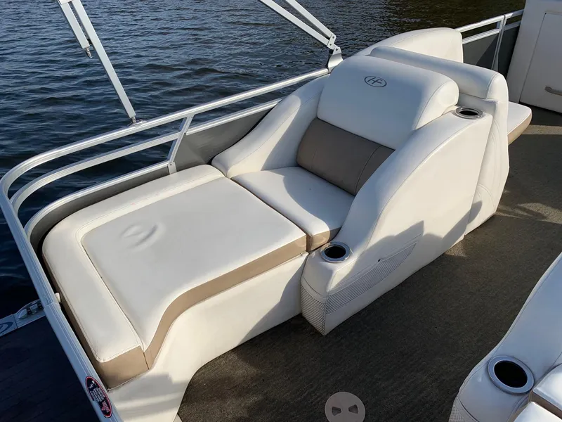 Slide: The Image of 2014 Harris Solstice 240 boat with white and beige seating by the water. - 8