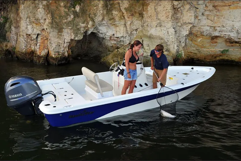 Slide: The Image of 2023 NauticStar 195 Bay boat with Yamaha motor, fishing near rocky shoreline. - 6