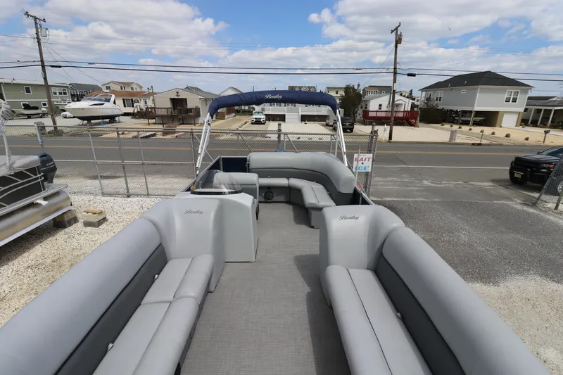 Slide: The Image of 2019 Bentley Pontoons 240/243 Cruise with spacious seating, docked near residential area under blue sky. - 6