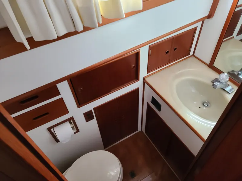 Slide: The Image of 1989 Grand Banks 42 Classic yacht bathroom with sink, toilet, and wooden cabinetry. - 14