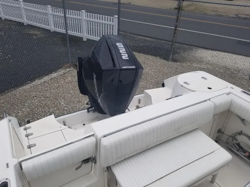 Slide: The Image of 2001 Boston Whaler 23 Outrage boat with outboard motor, docked near a fence. - 8