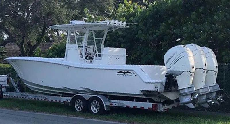 The Image of Invincible 33 boat on trailer, triple engines, parked outdoors, 2008 model. - 0