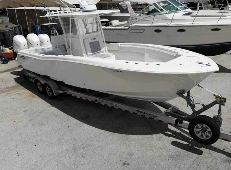 Slide: The Image of 2008 Invincible 33 boat on trailer, triple engines, docked beside other boats. - 6
