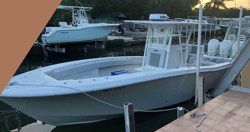 Slide: The Image of 2008 Invincible 33 boat docked, featuring a sleek white design and twin engines. - 7