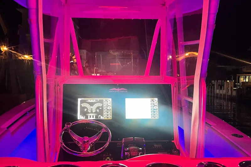 Slide: The Image of Cockpit of 2008 Invincible 33 boat illuminated with vibrant pink lighting at night. - 9