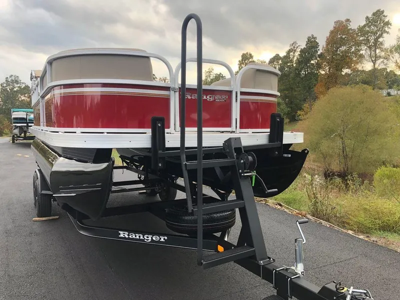 Slide: The Image of 2023 Ranger 200C pontoon boat on trailer, red and white, parked on asphalt. - 15