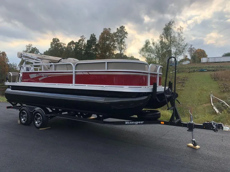 Slide: The Image of 2023 Ranger 200C pontoon boat on a trailer, parked outdoors. - 3