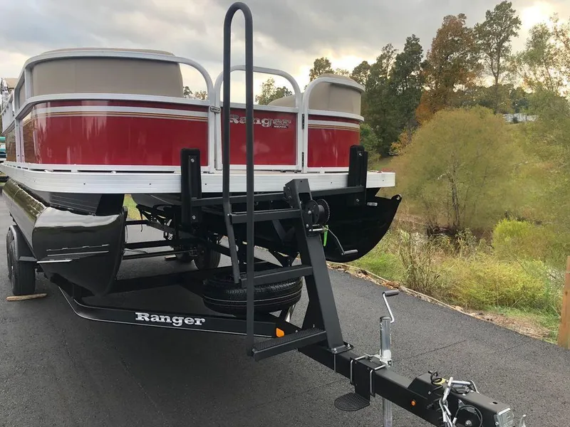 Slide: The Image of 2023 Ranger 200C pontoon boat on trailer, red and white, parked on asphalt. - 4