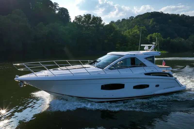 Slide: The Image of 2015 Regal 53 Sport Coupe cruising on a scenic river with lush greenery. - 12