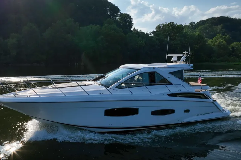 Slide: The Image of 2015 Regal 53 Sport Coupe cruising on a scenic waterway with lush greenery. - 13