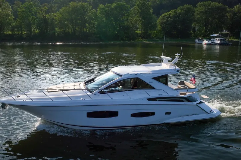 Slide: The Image of 2015 Regal 53 Sport Coupe cruising on a serene lake with lush green backdrop. - 17