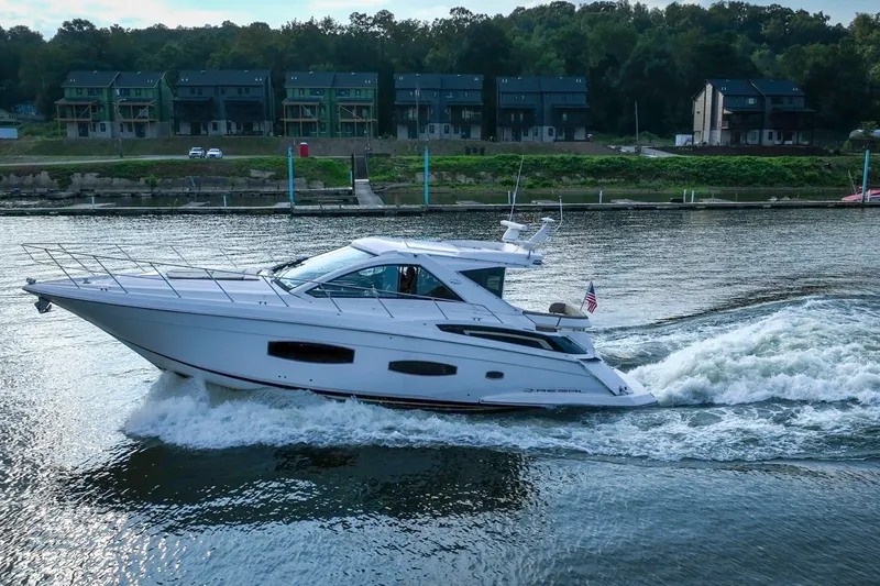 Slide: The Image of 2015 Regal 53 Sport Coupe cruising on a river with houses in the background. - 20