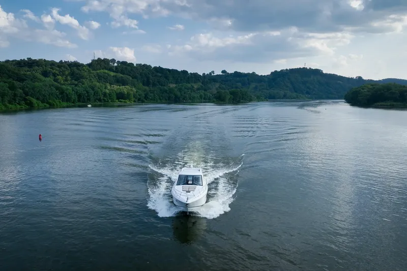 Slide: The Image of 2015 Regal 53 Sport Coupe cruising on a scenic river with lush green hills. - 22
